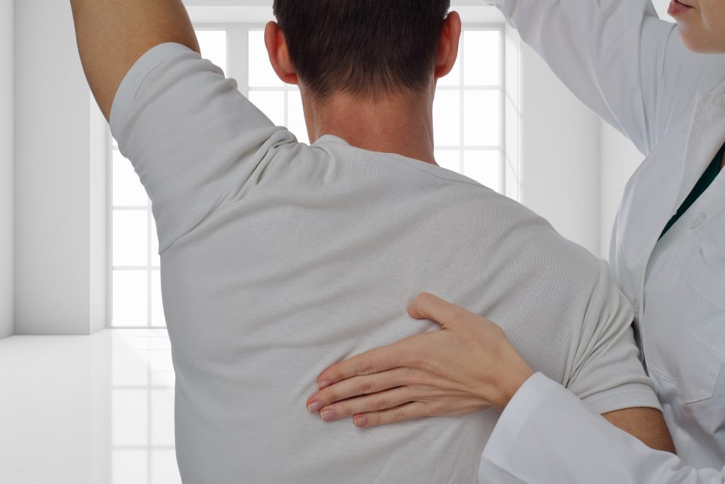 Fyzioerapeutka pomáha mužovi s jeho bolesťou v strednej časti chrbta.